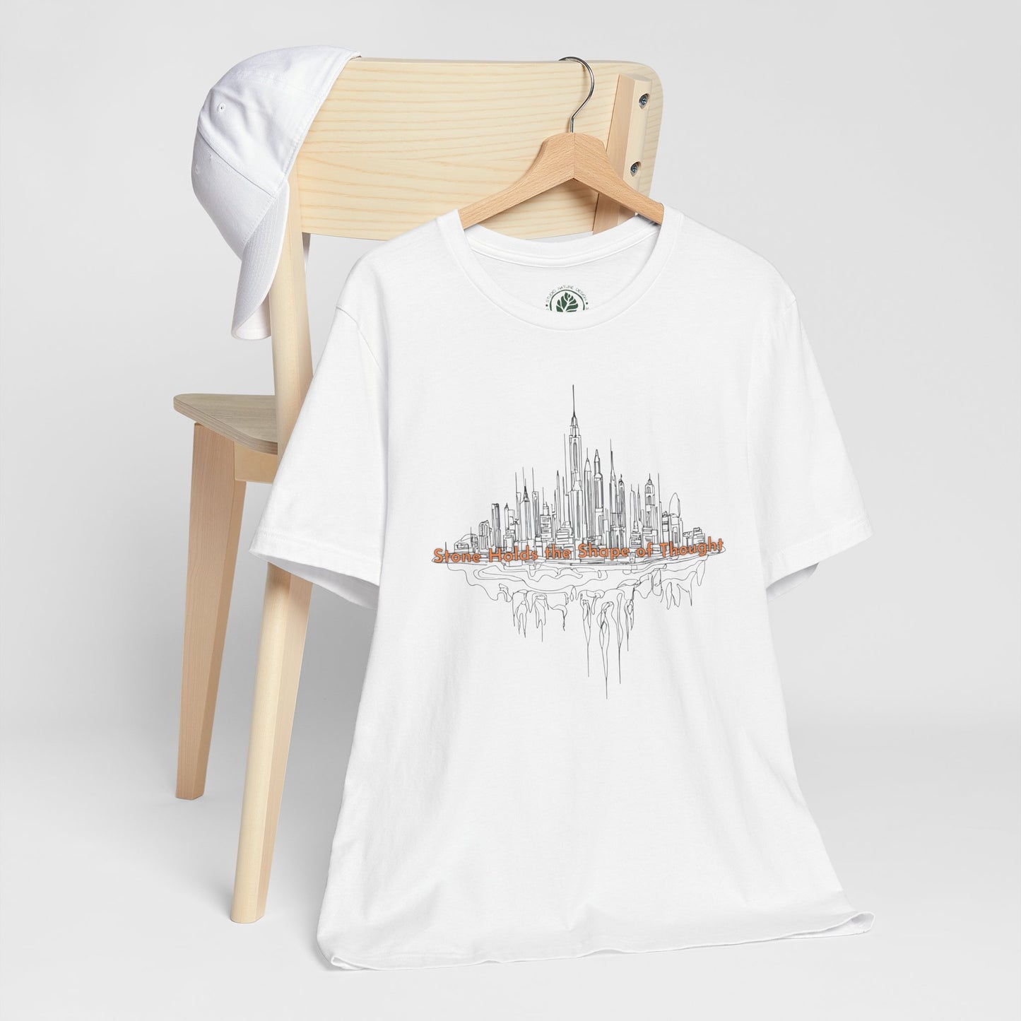 White t-shirt with city skyline design on a wooden chair against a white background