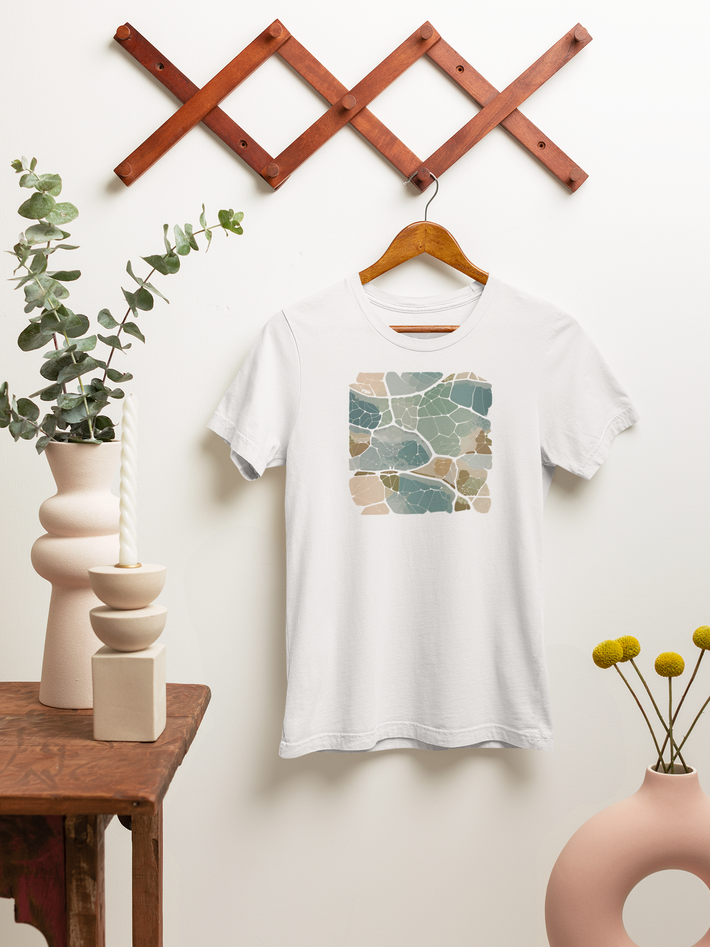 White t-shirt with a geometric biomimicry urban design pattern on a hanger against a white wall with decorative elements.
