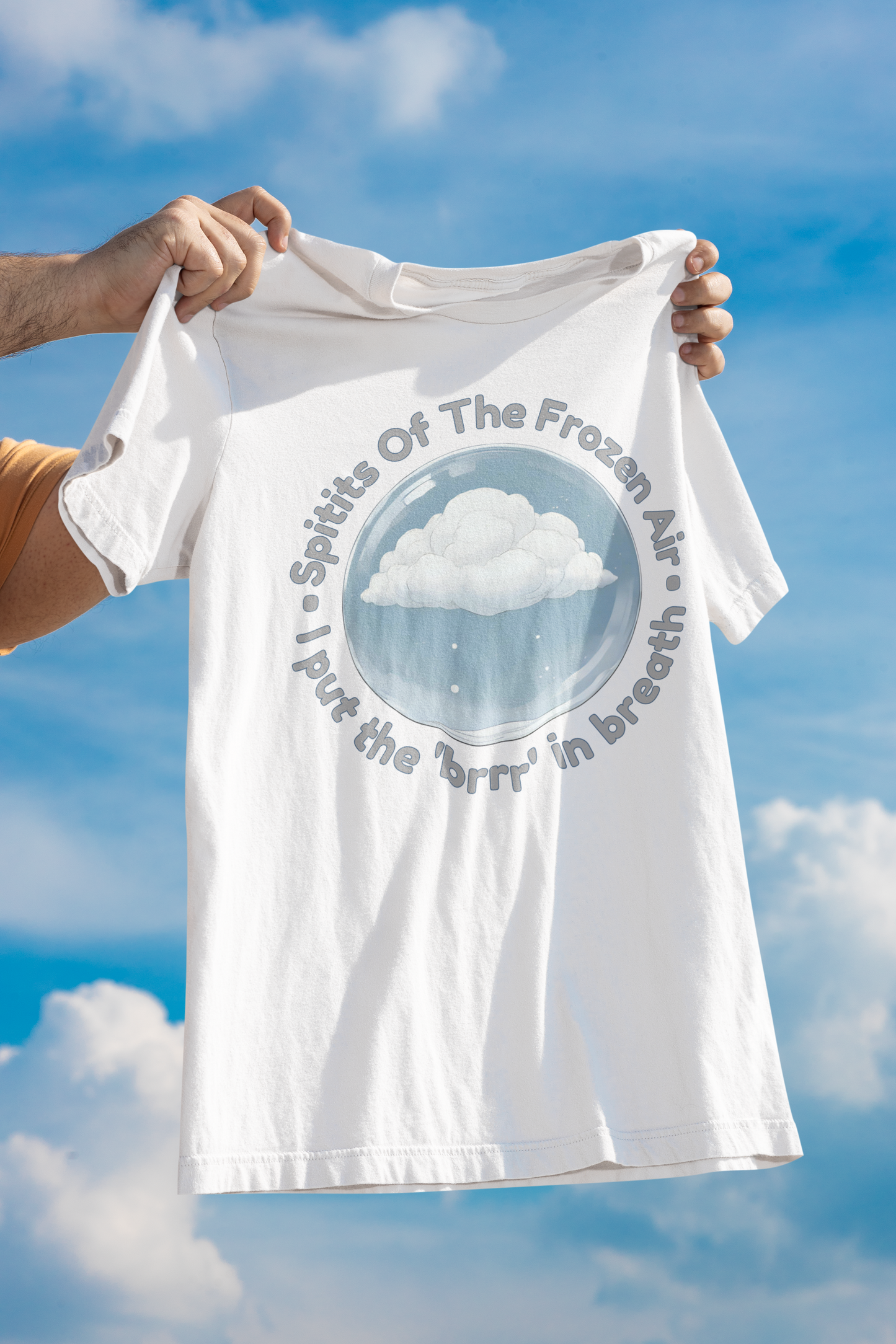 White t-shirt with cloud design and text held against a blue sky
