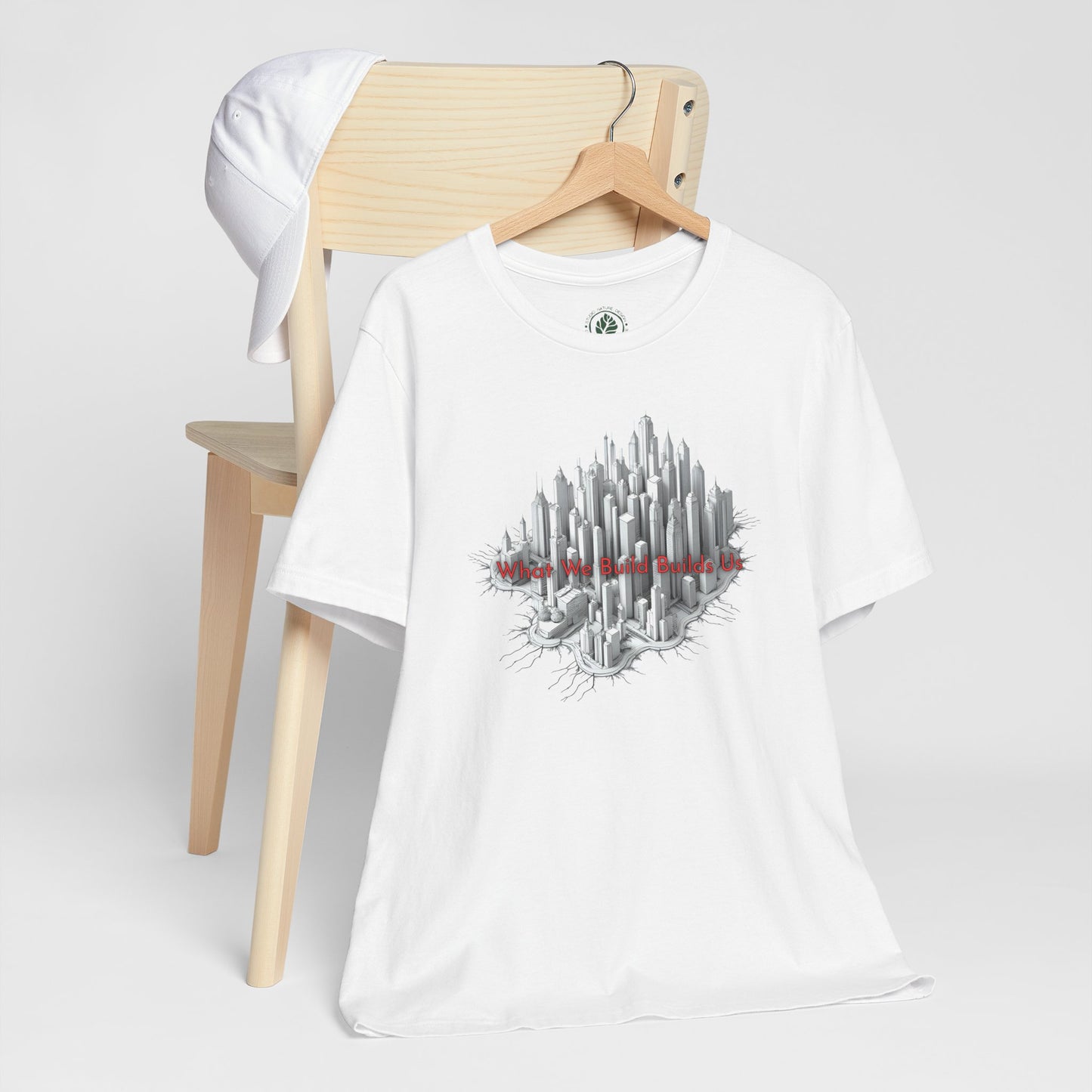 White t-shirt with cityscape graphic design on a wooden chair against a white background
