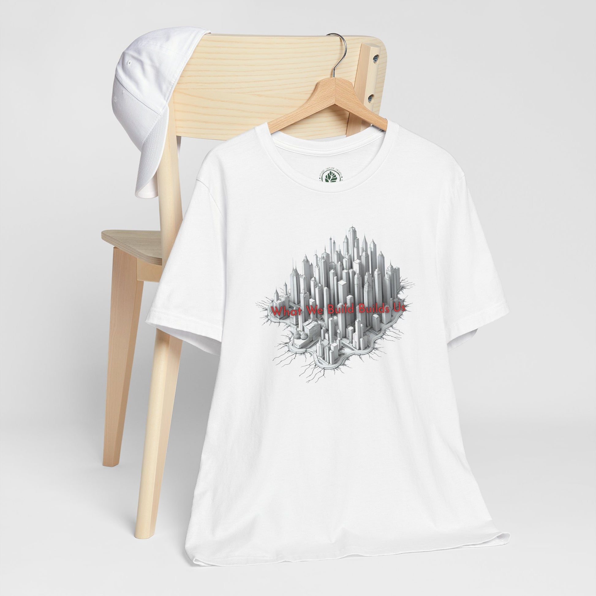 White t-shirt with cityscape graphic design on a wooden chair against a white background