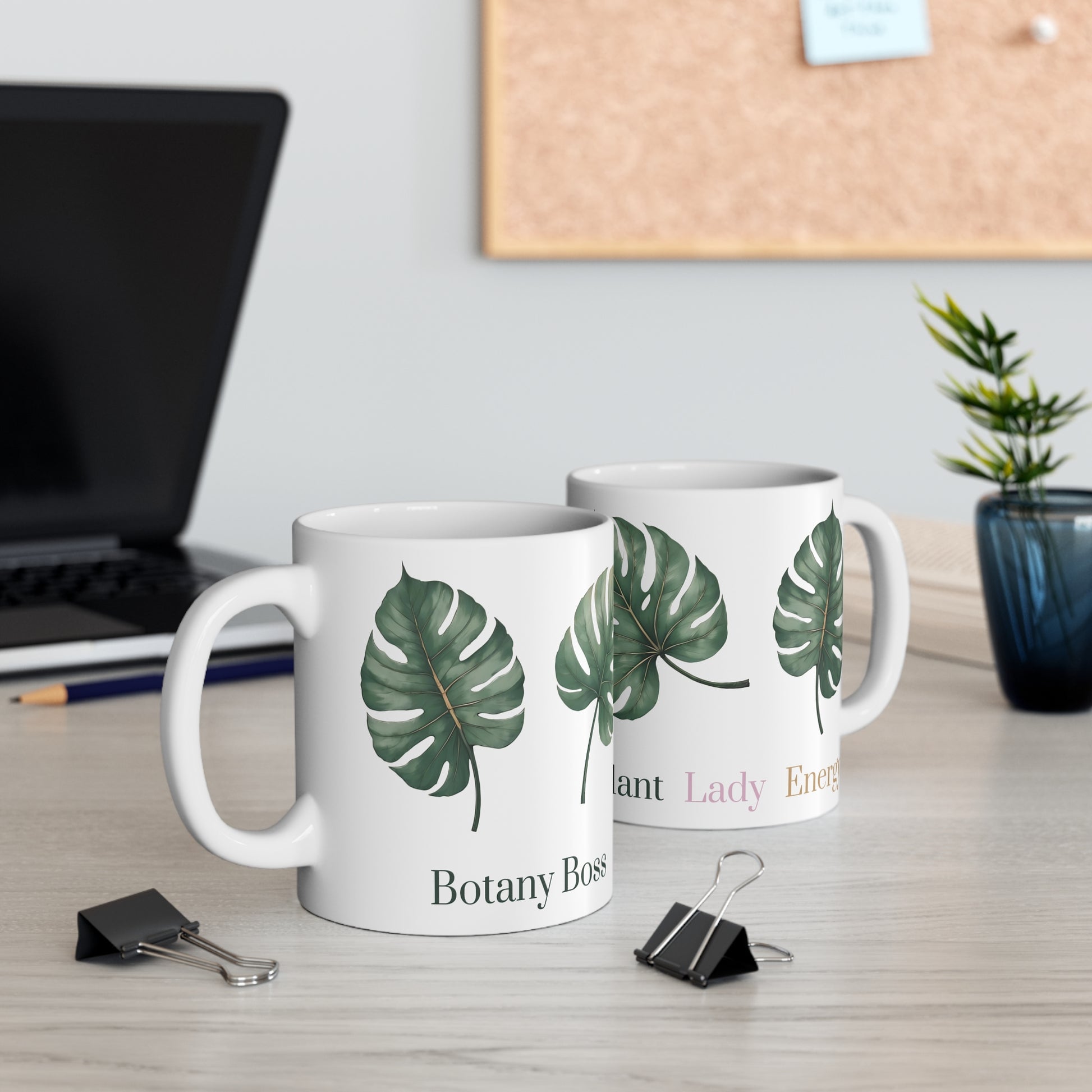 White ceramic mug featuring four evenly arranged monstera leaves. One side displays the phrase 'Plant Lady Energy,' while the other reads 'Botany Boss.' Ideal for plant lovers and indoor gardeners.