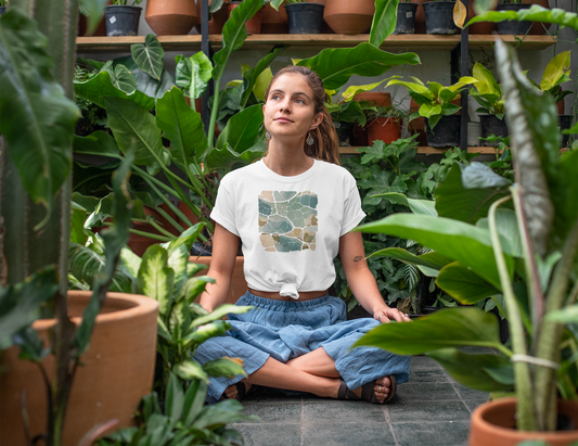 A women sitting cross-legged among potted plants wearing a white t-shirt with a biomimicry urban design.