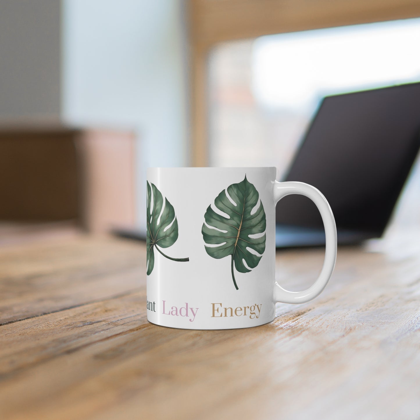 White ceramic mug featuring four evenly arranged monstera leaves. One side displays the phrase 'Plant Lady Energy,' while the other reads 'Botany Boss.' Ideal for plant lovers and indoor gardeners.