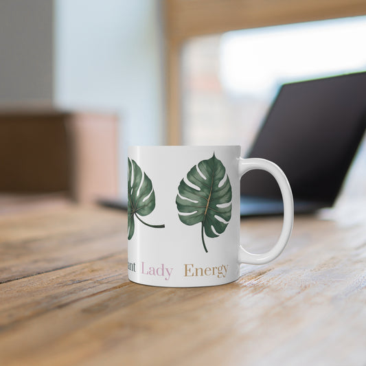 White ceramic mug featuring four evenly arranged monstera leaves. One side displays the phrase 'Plant Lady Energy,' while the other reads 'Botany Boss.' Ideal for plant lovers and indoor gardeners.
