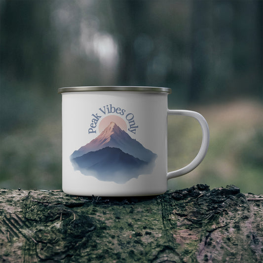 White enamel camping mug with minimalist mountain design and the quote “The summit’s not the goal — it’s the space where heart and earth converge,” displayed outdoors on a rustic surface, evoking hiking, wilderness, and nature-inspired living.