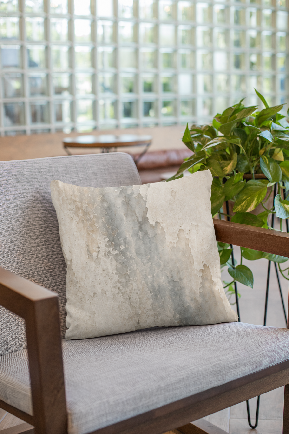 Rain Memory faux suede pillowcase on a light grey armchair beside green plants in a bright interior.
